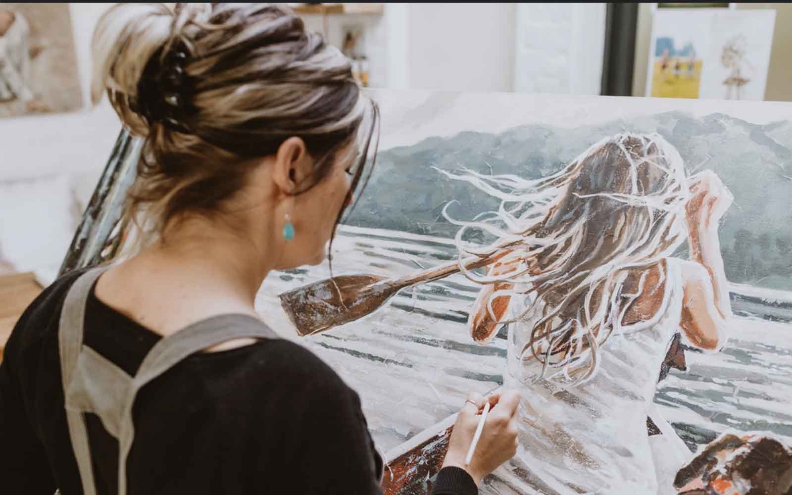 Image of Maria busy doing a painting of a woman rowing a boat